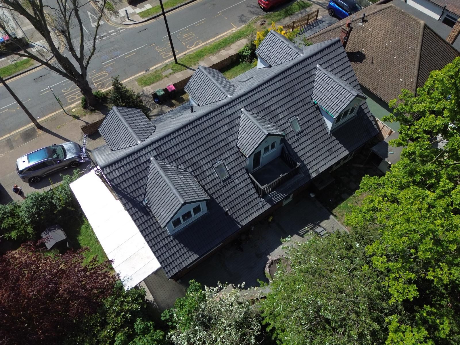 Aerial view of a completed grey tiled roof with multiple dormers by Direct Roofing